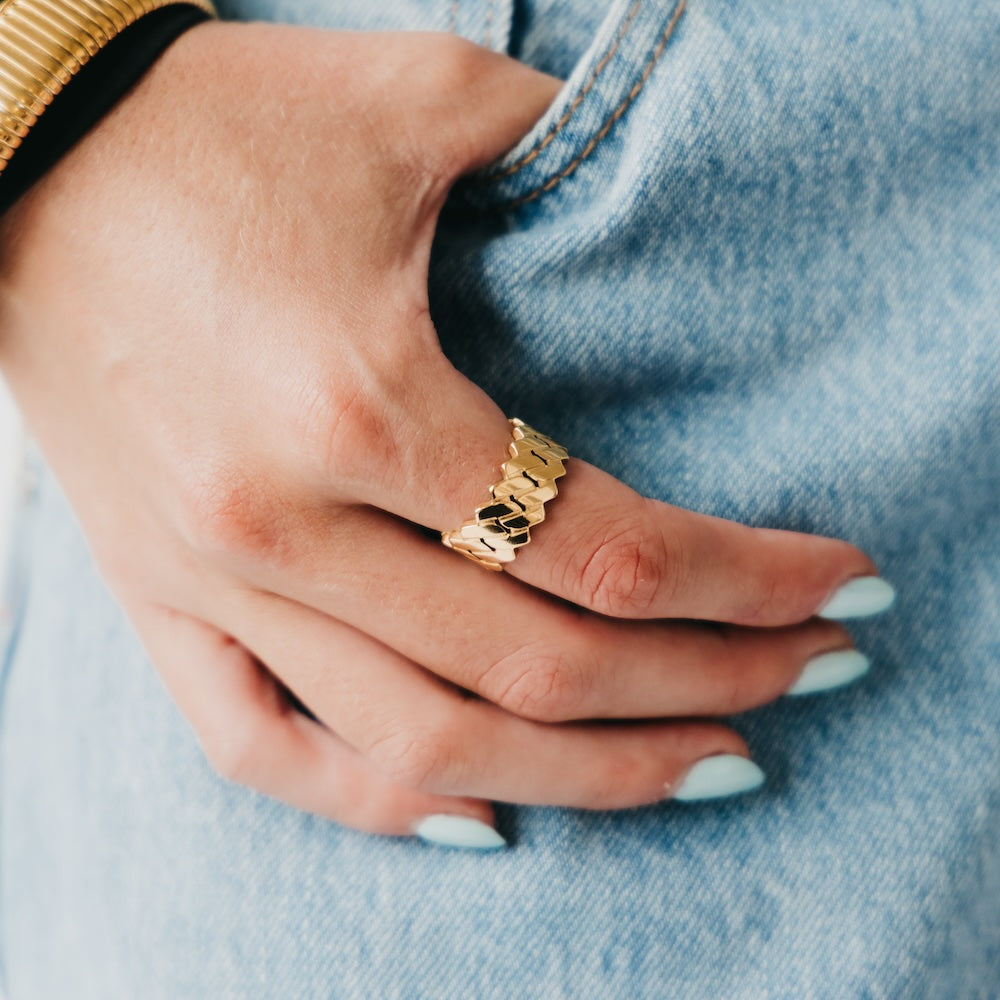 Gold-tone metal statement ring with patterned band, worn on hand