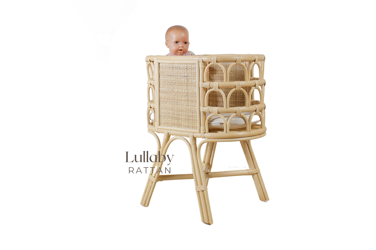 Natural rattan doll crib with woven panels and open arched sides, shown from the opposite side