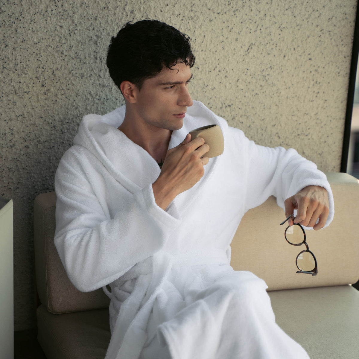 Unisex plush white hooded cotton bathrobe, belt tied, sleeves down