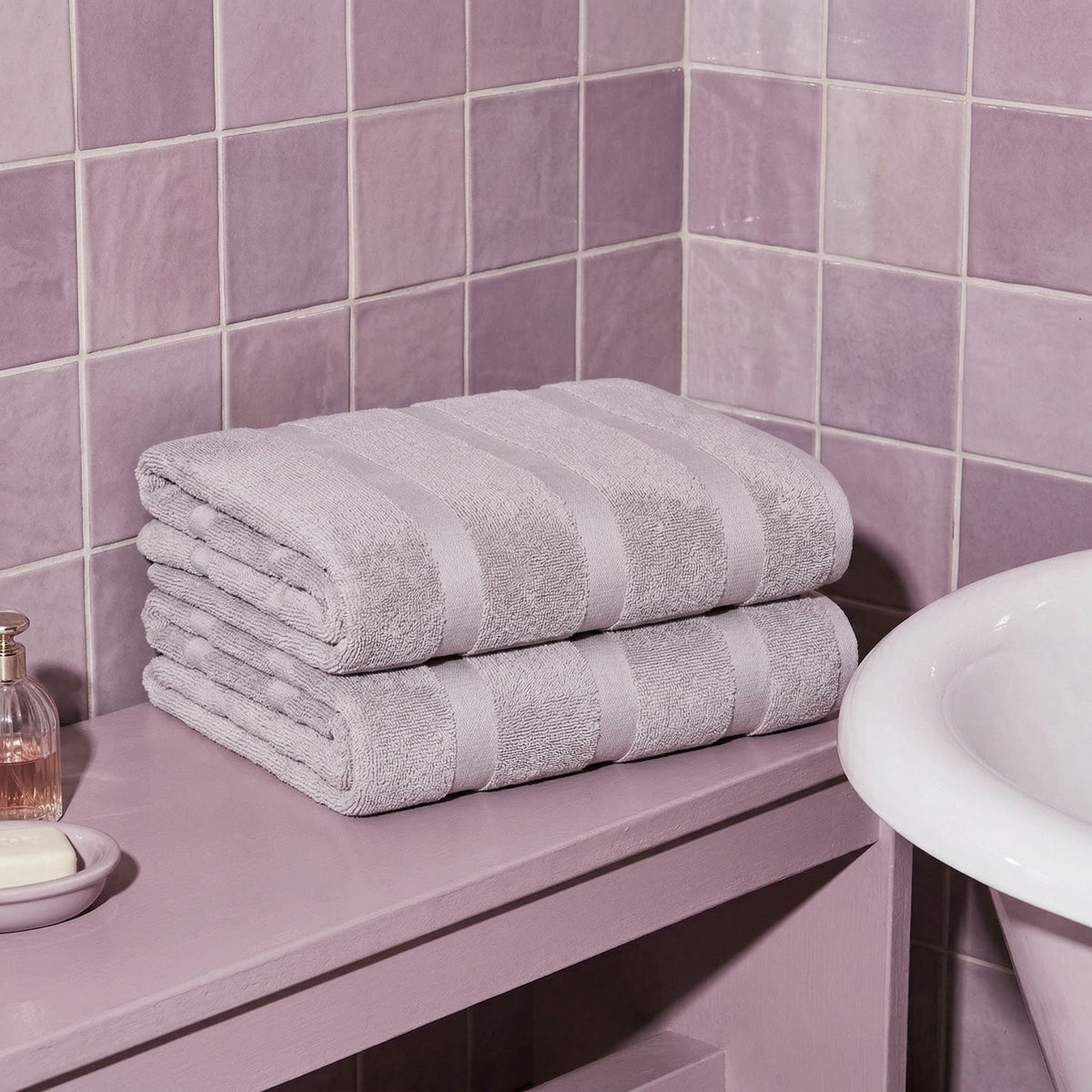 Lilac cotton bath towel stack with stitched stripe bands, neatly folded