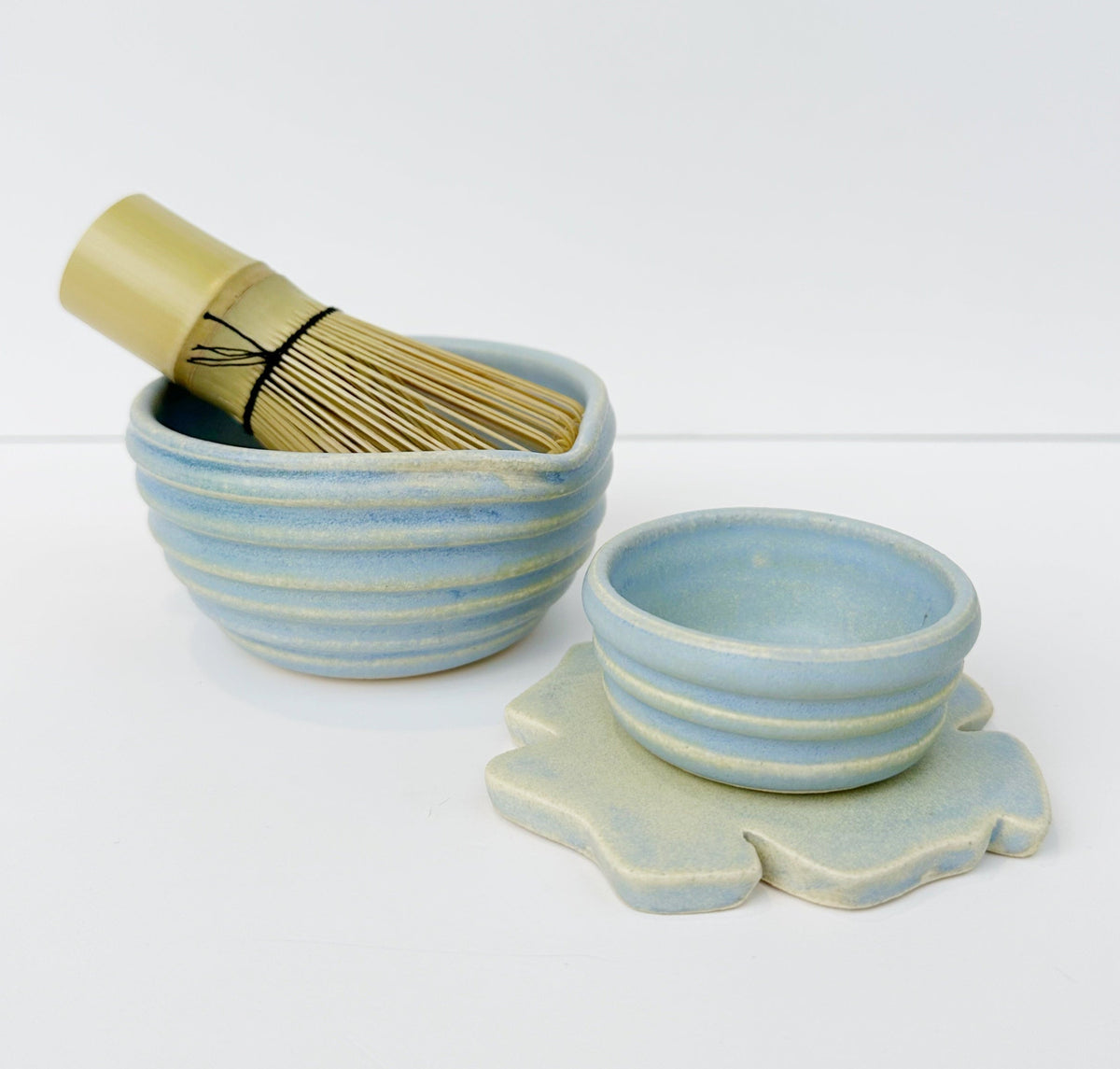 Blue ceramic matcha bowls with ribbed texture, plus whisk and scalloped mini cup