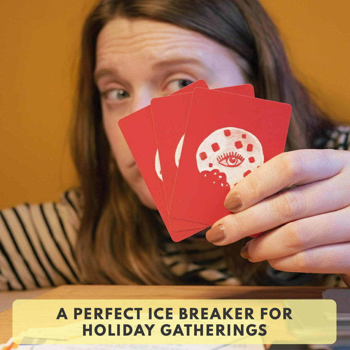 Woman holding red trivia cards with white holiday graphic