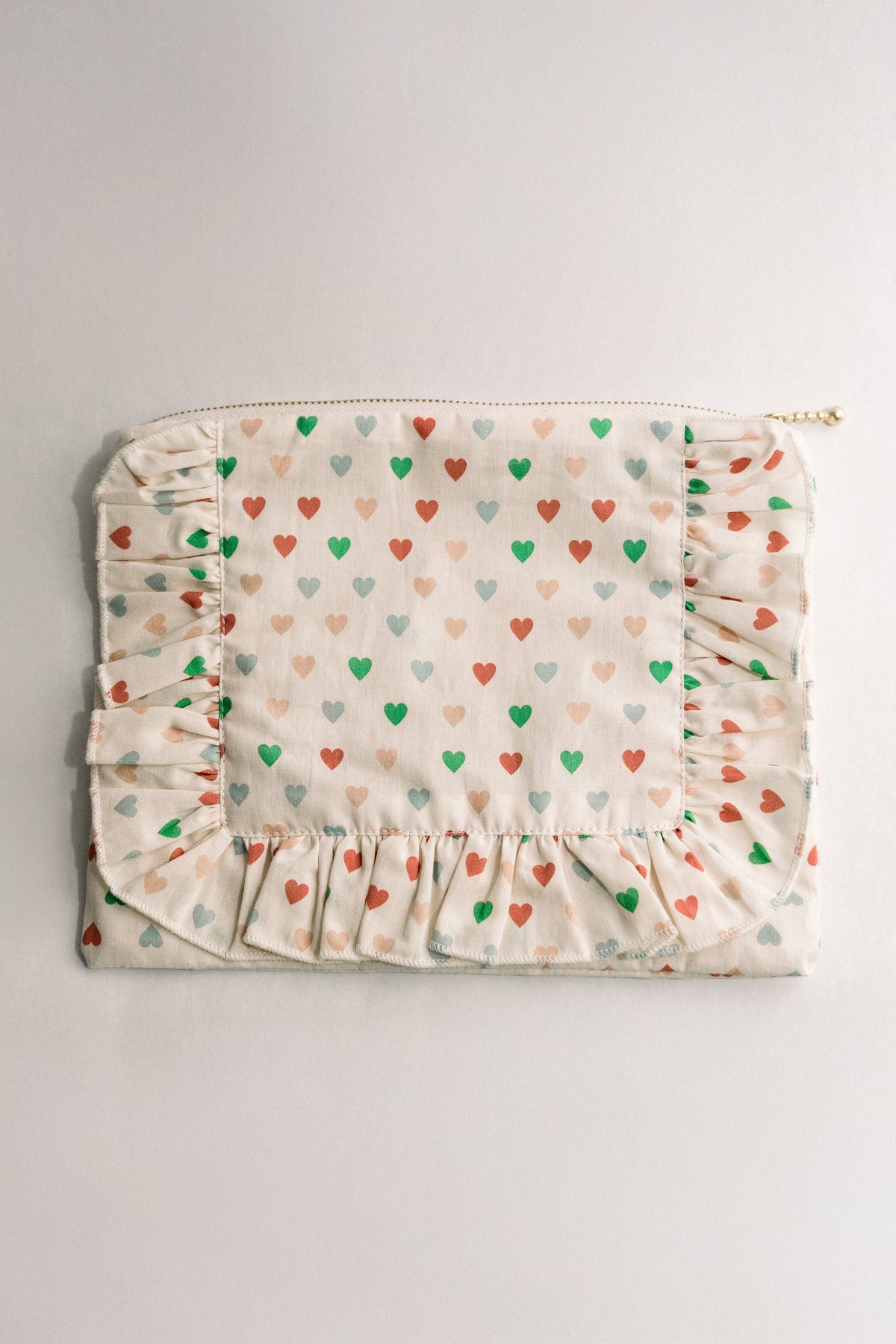 Heart-print ruffle zipper pouch front view with gathered trim and zipper pull