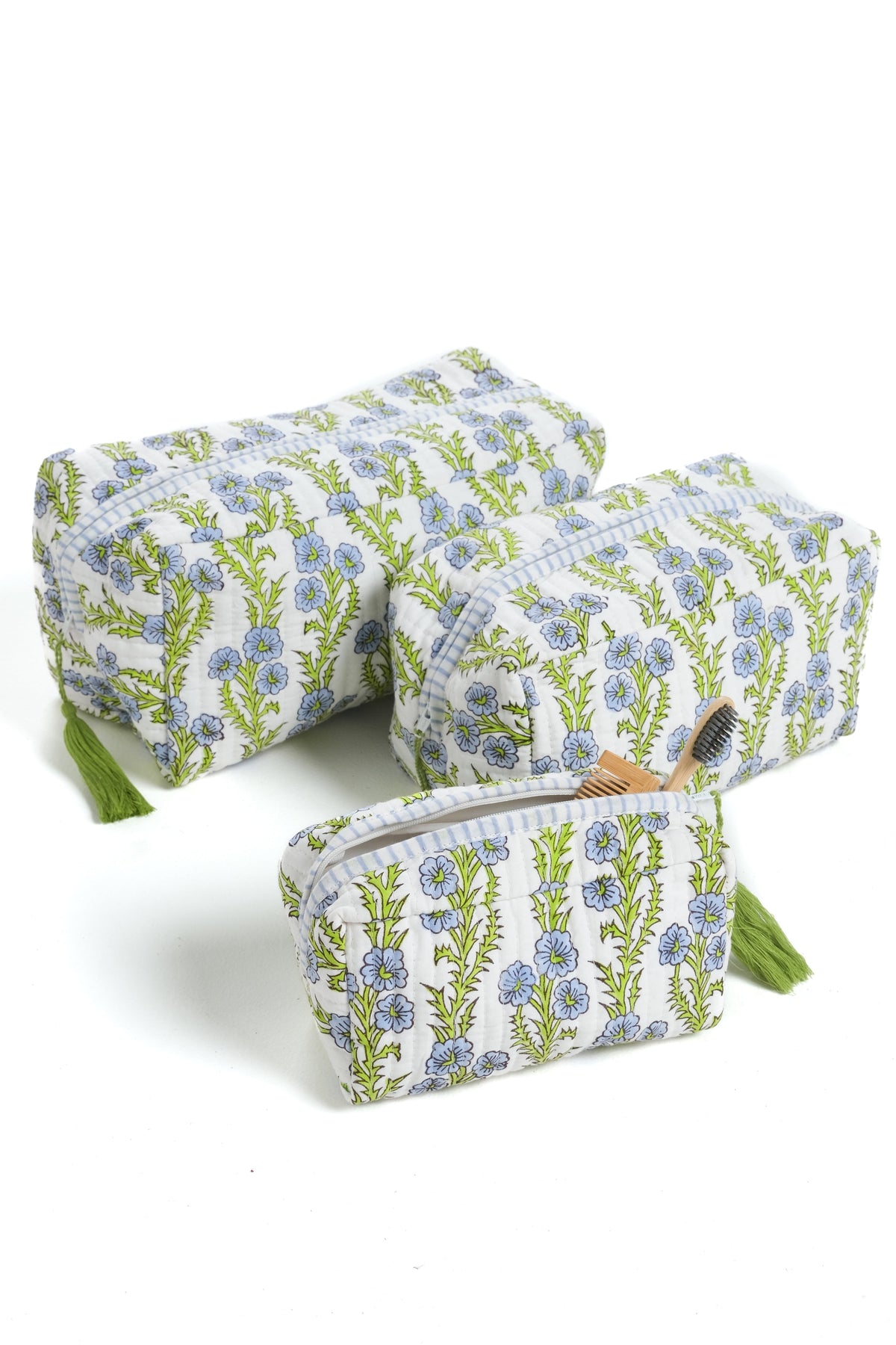 Blue floral blockprint makeup bag with zipper and green tassel, angled view.