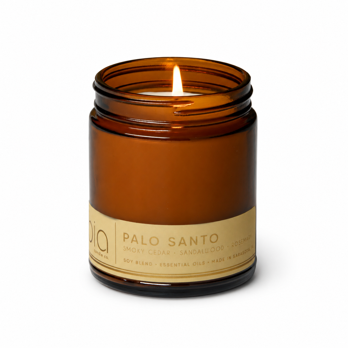 Amber glass soy candle jar with burning flame and gold “Palo Santo” label