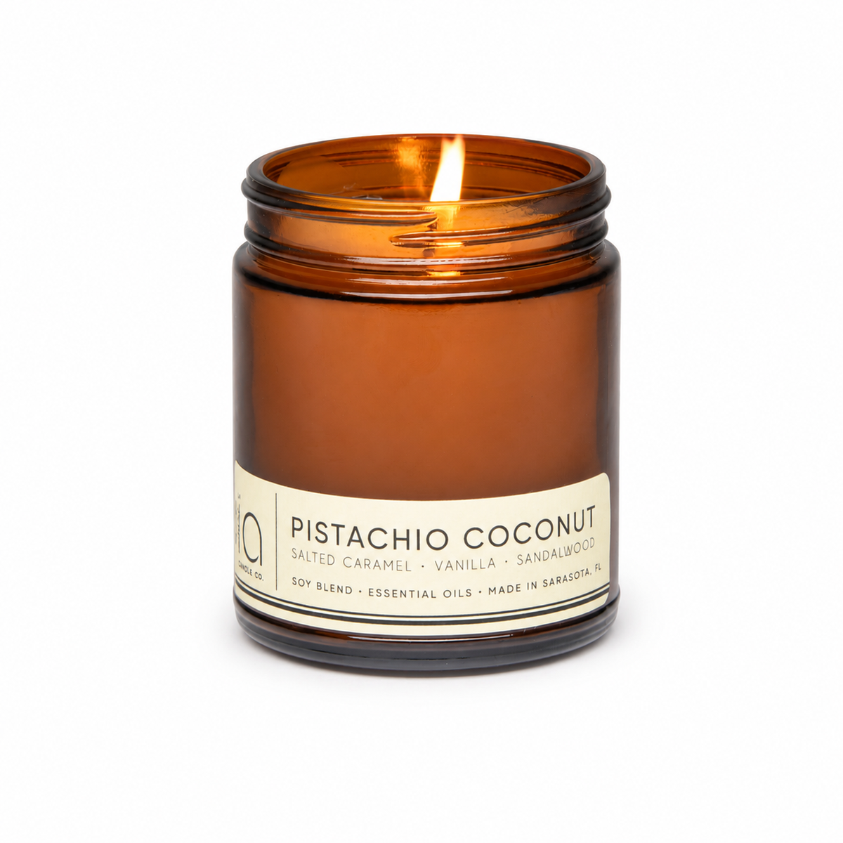 Pistachio coconut soy blend candle in amber glass jar, flame centered on top.