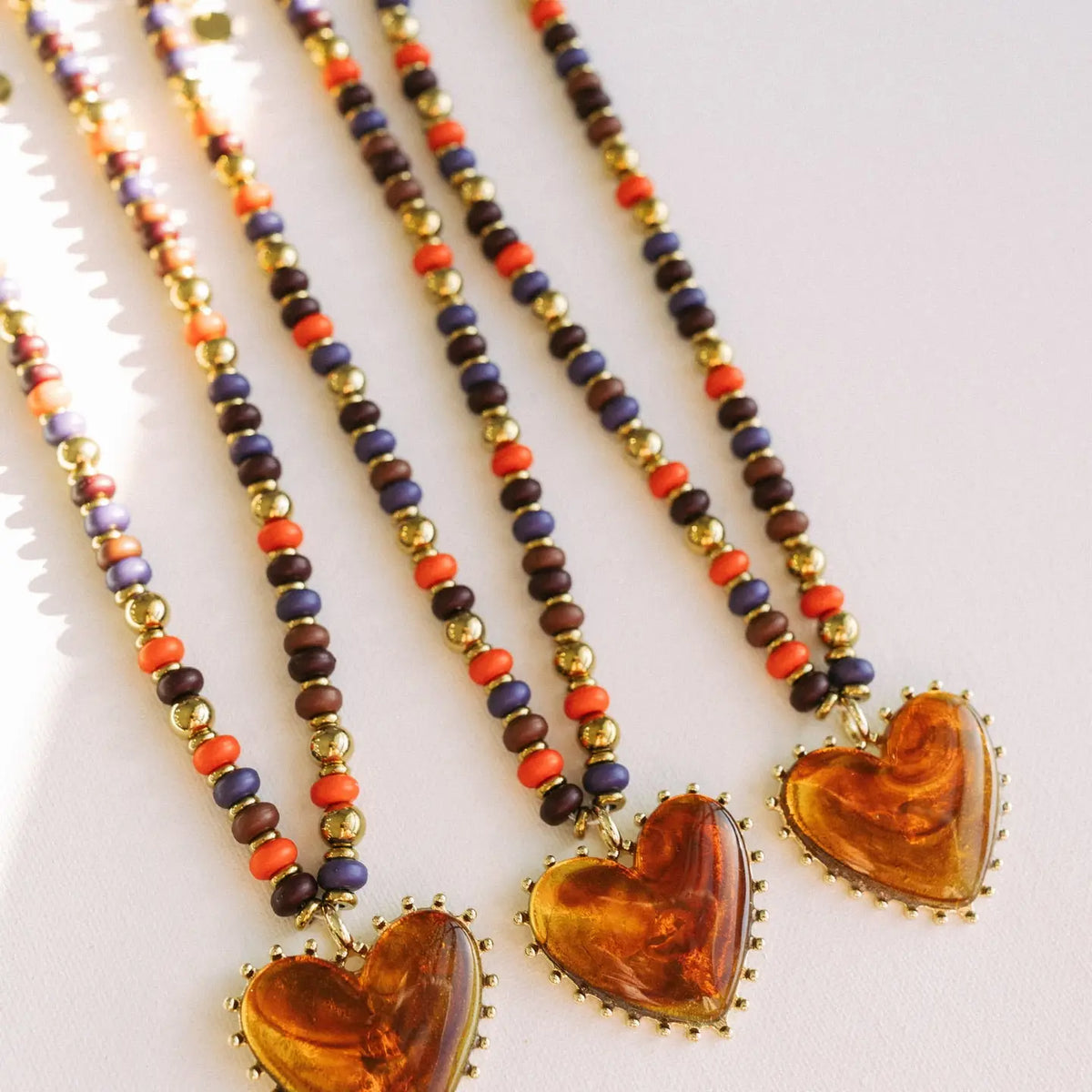 Amber heart pendant necklaces with multicolored beads and gold-tone edging