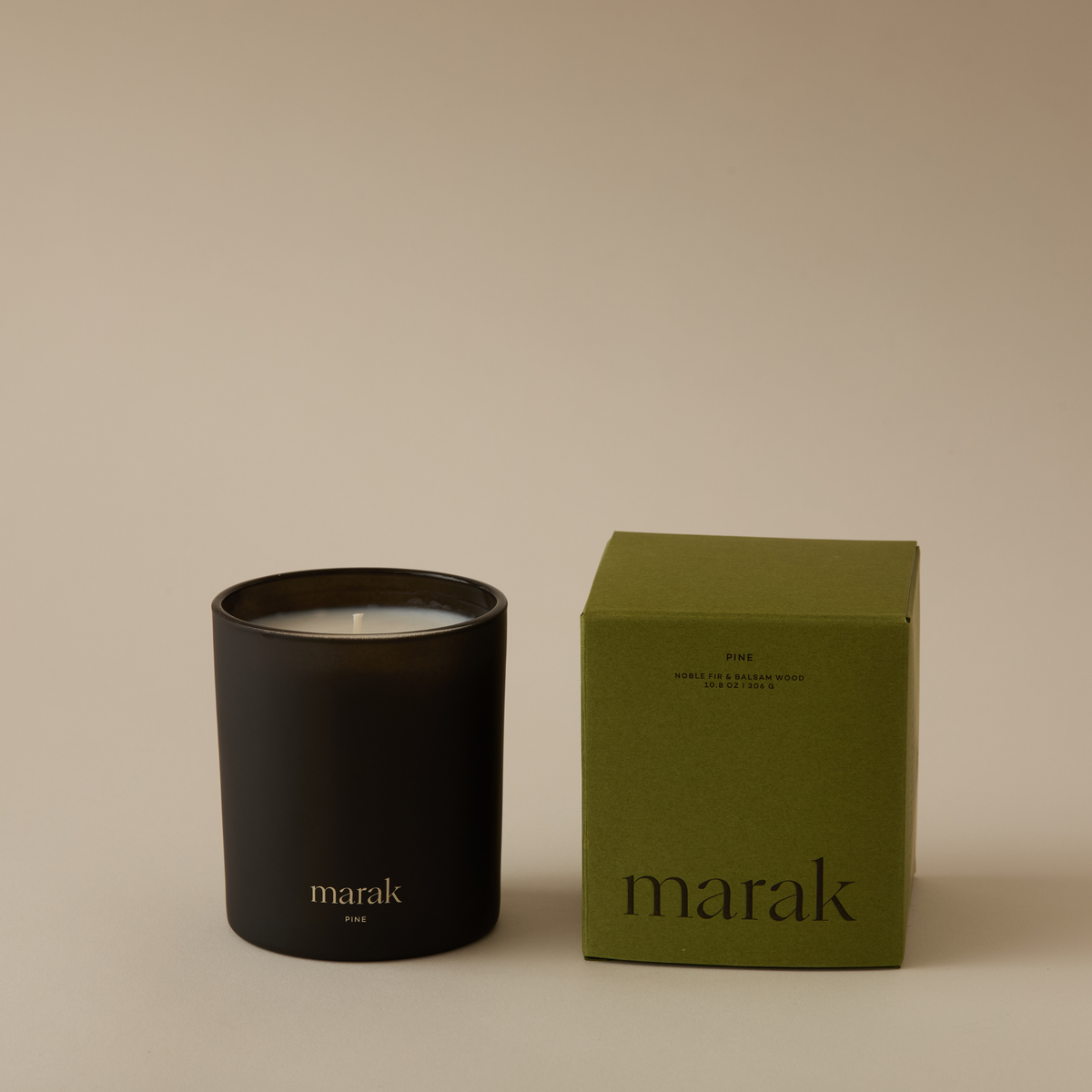Black marak candle jar with flame beside green marak candle box