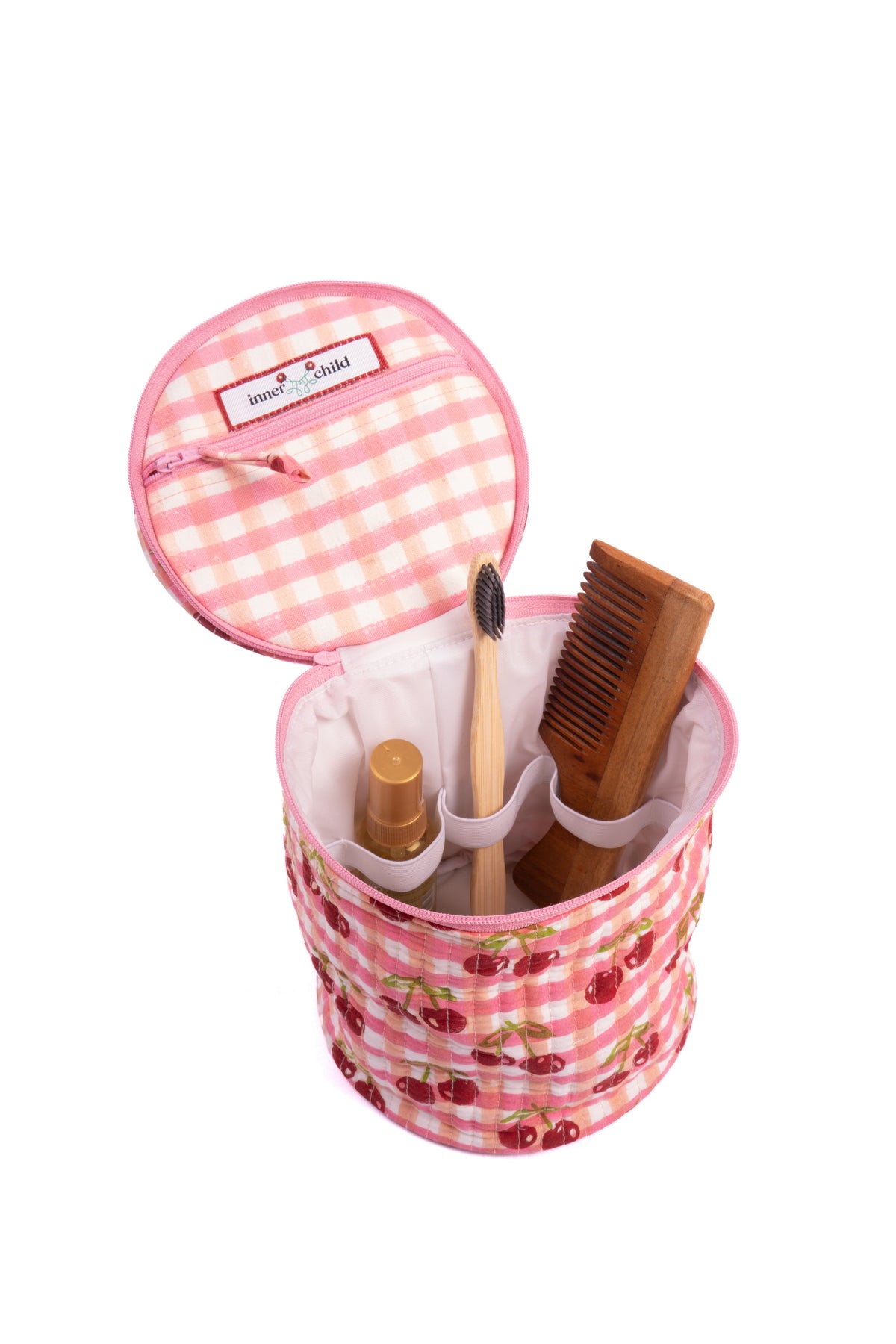 Upright round makeup bag open with brushes inside and cherry gingham print