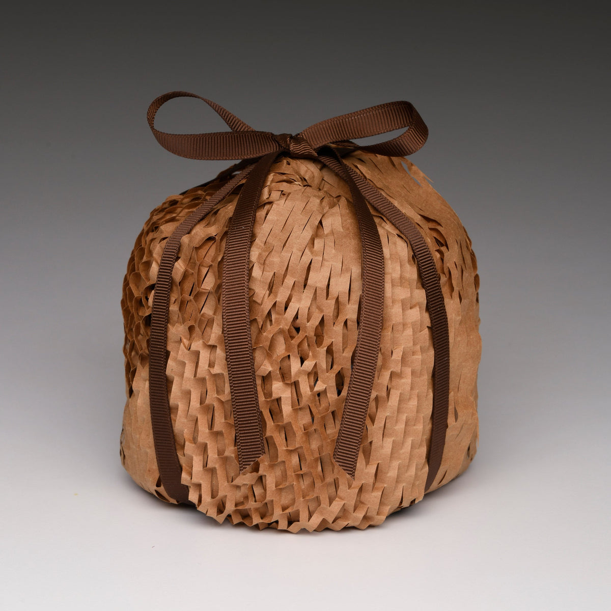 Kraft paper-wrapped candle with woven texture and dark brown ribbon bow
