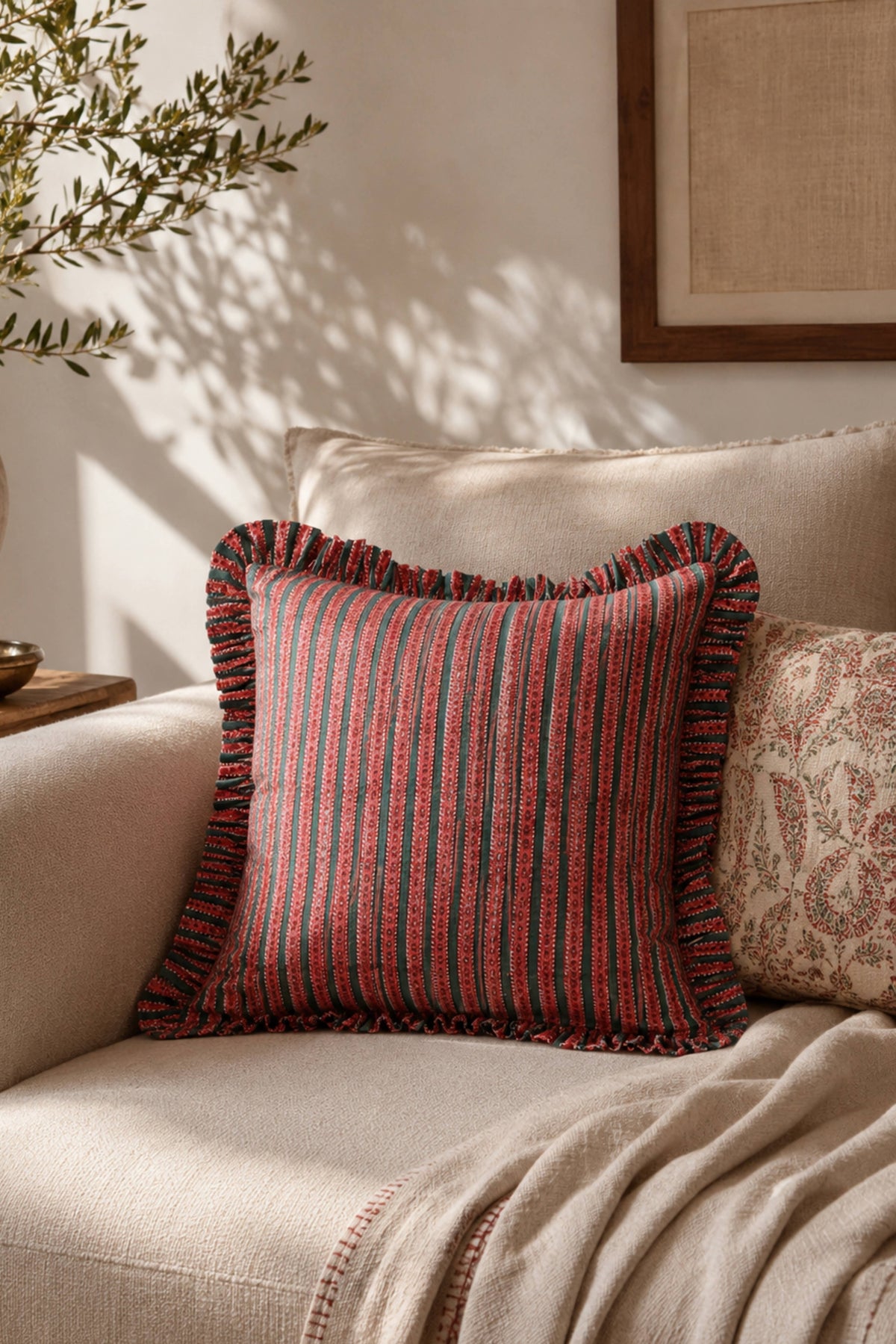 Ruffle-edged striped pillow cover in crimson and teal tones on a sofa