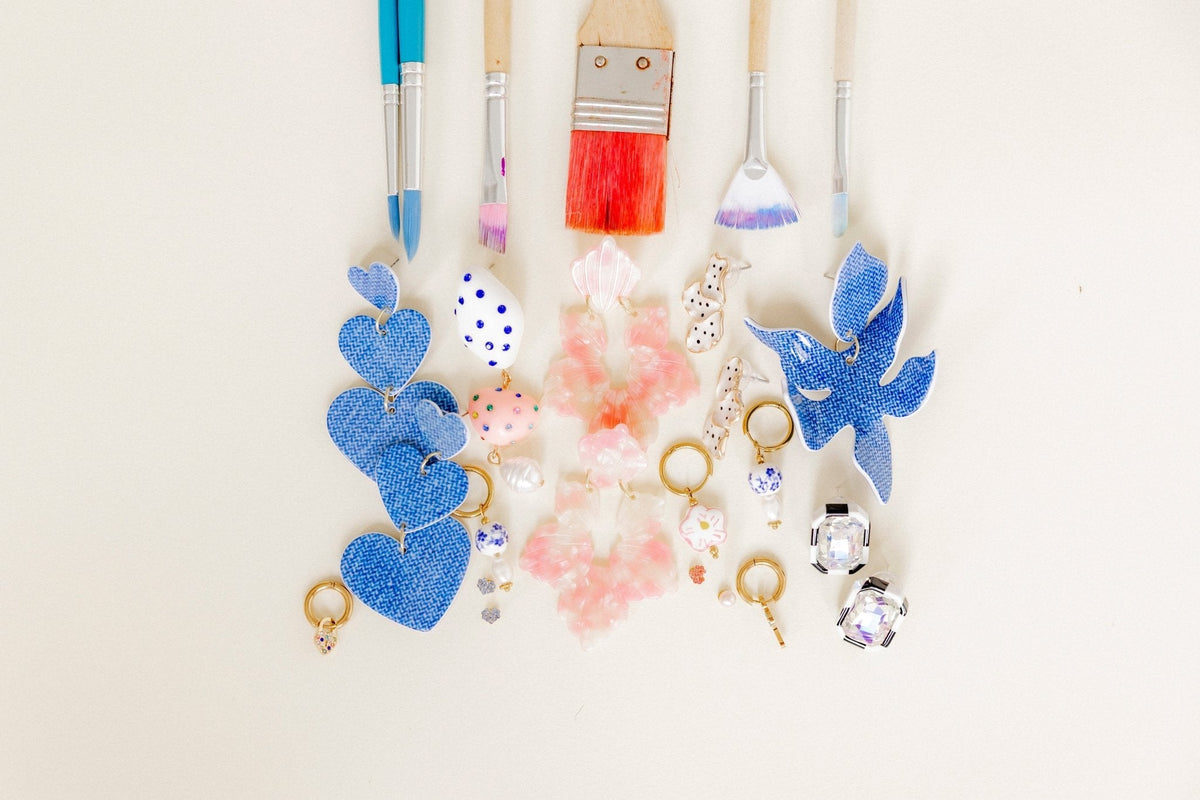 Assorted statement earrings laid out: blue hearts, pink details, and crystal drops