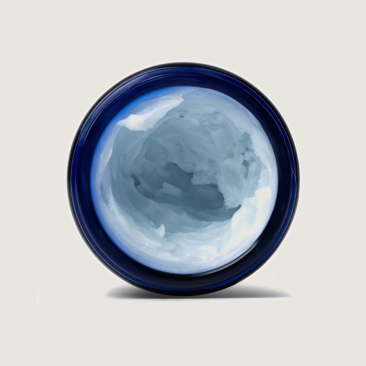 Top view of blue-tinted whipped balm inside a blue-lidded jar