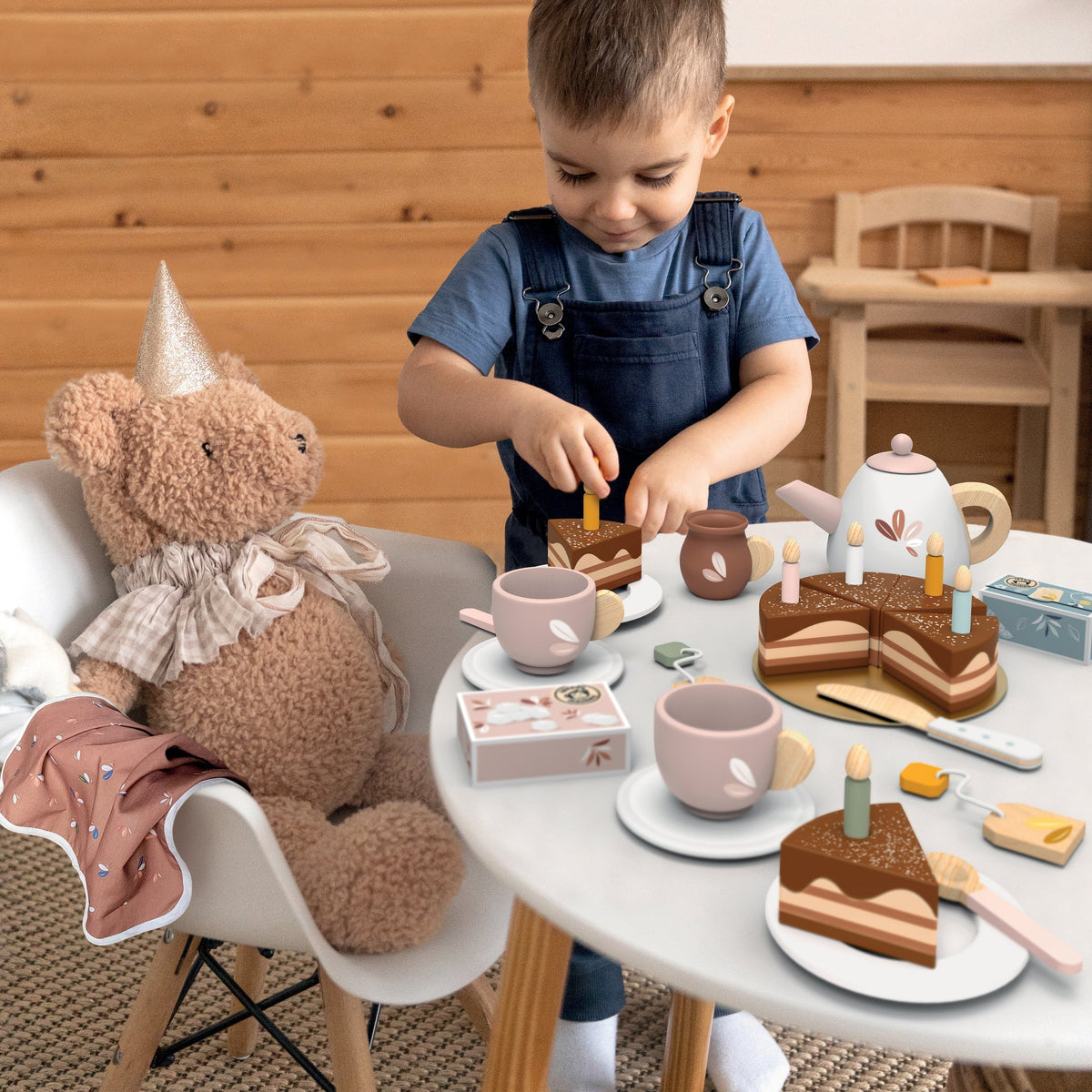 Tea set playset with teapot, cups, cakes, and candles on a table during pretend play