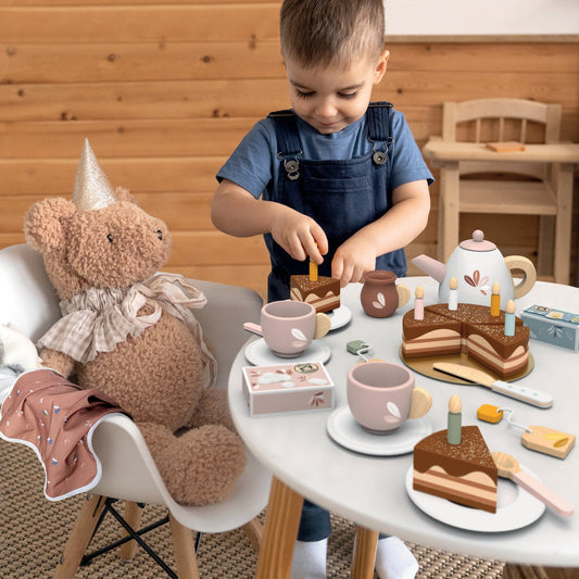 Tea set playset with teapot, cups, cakes, and candles on a table during pretend play
