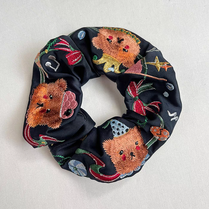 Black scrunchie with embroidered circus bear faces, stars, and colorful ribbon details