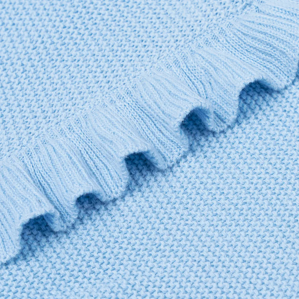 Close-up of baby blue knit blanket showing texture and ruffled edge trim