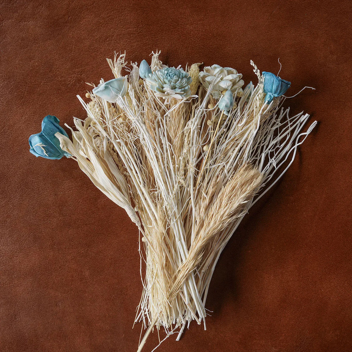 Triangular dried grass bouquet with white and pale blue blooms