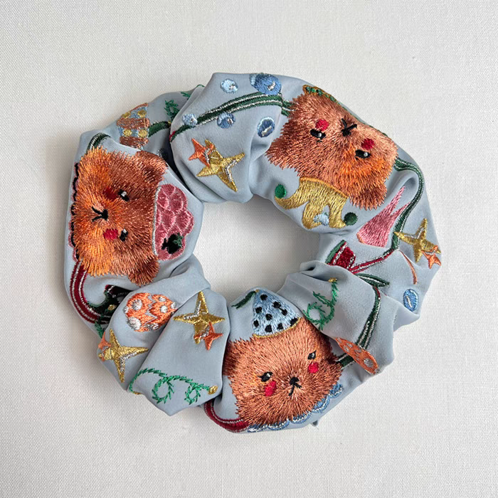 Light blue scrunchie with embroidered bear faces, hearts, and gold star accents