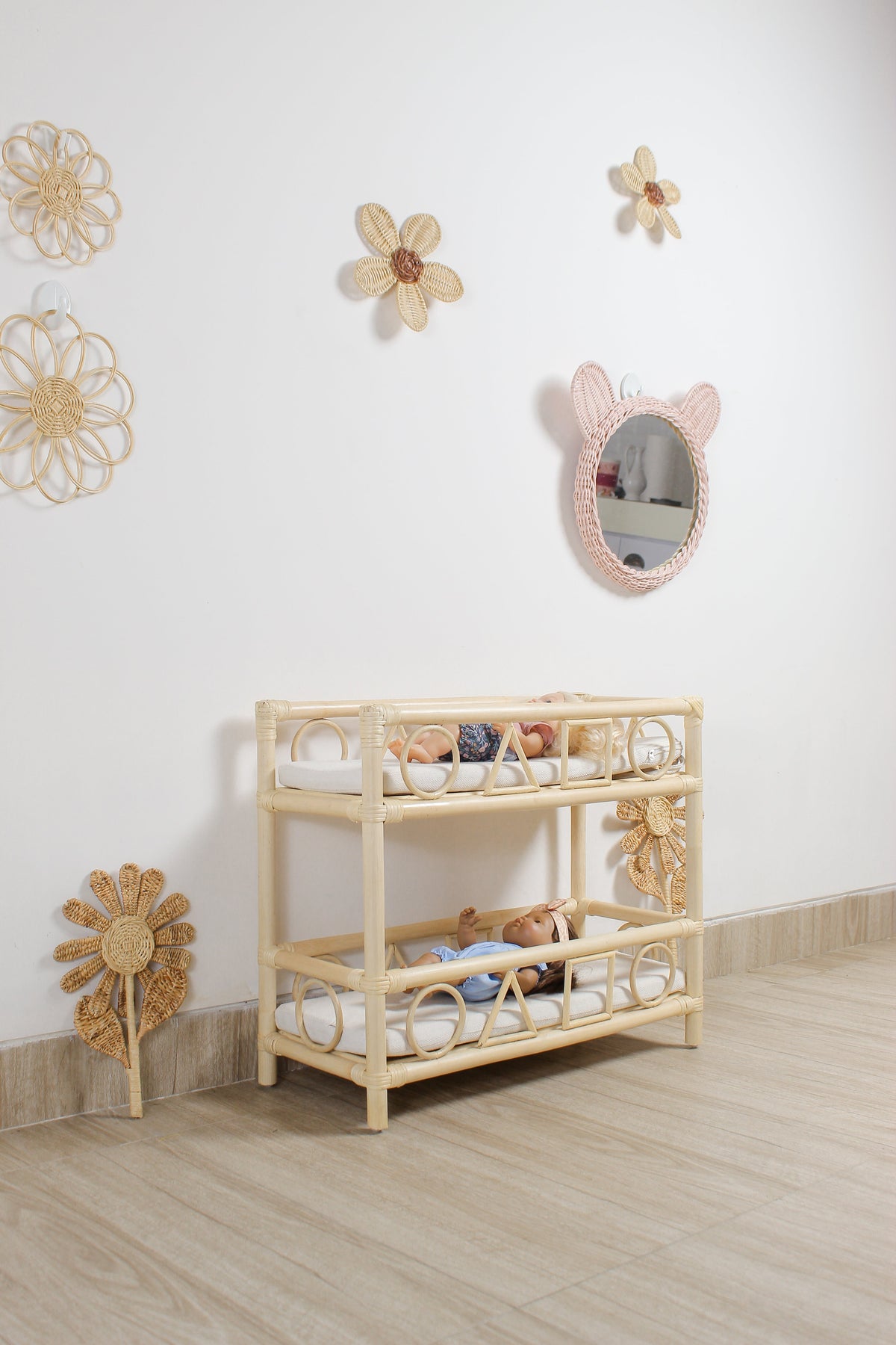 Pink rattan teddy bear wall mirror above a two-tier nursery shelf