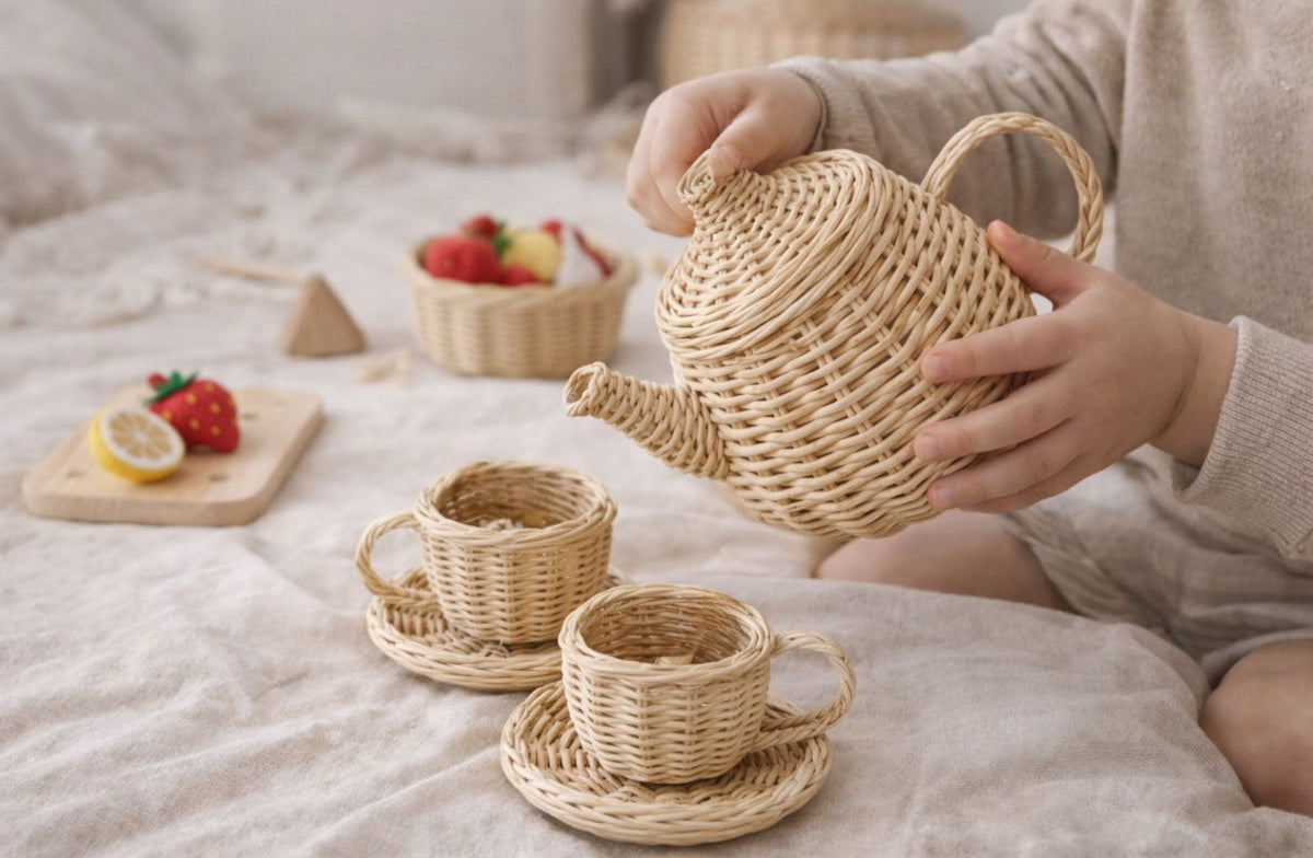 Wicker toy teapot and two cups with saucers in a child's hands