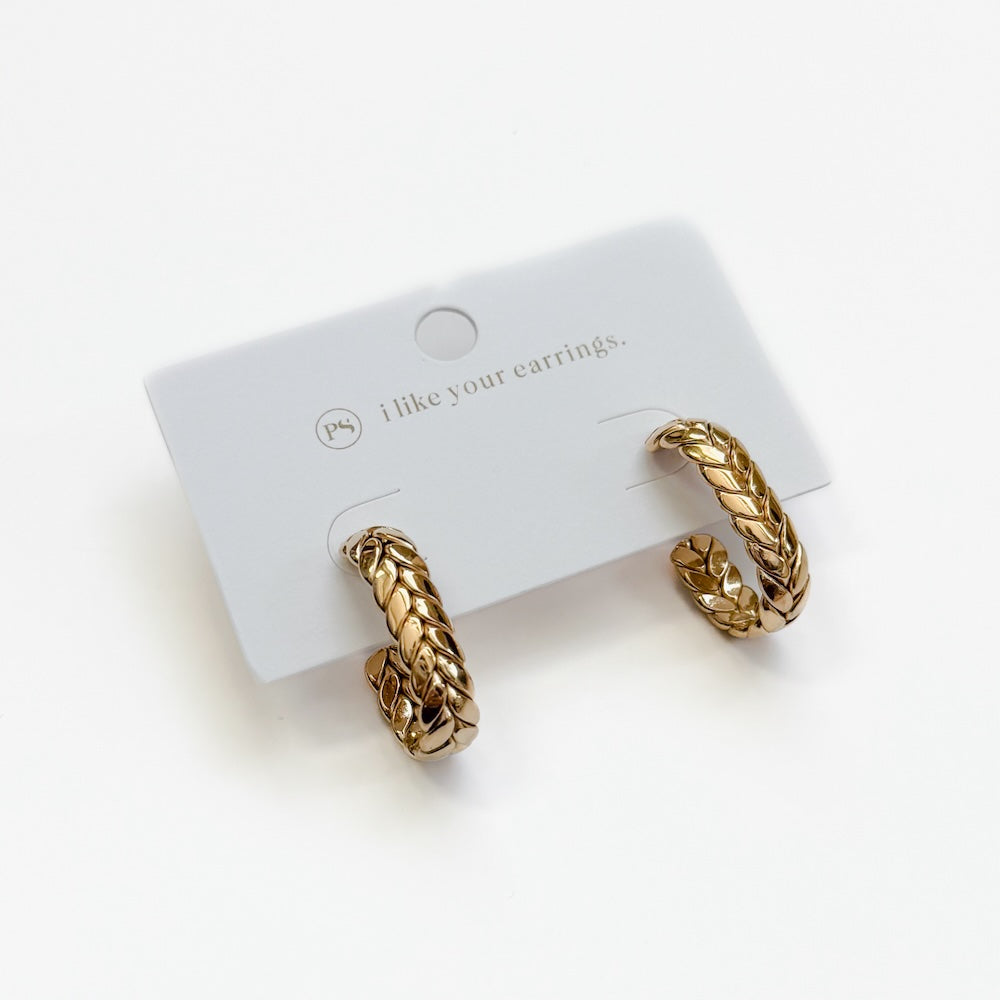 Gold braided oval hoop earrings pair displayed on card.