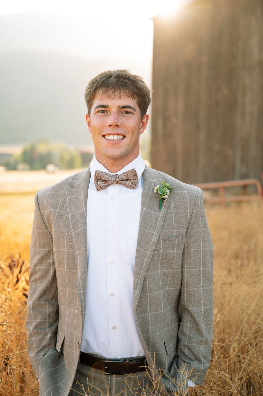 Men's pre-tied bow tie with floral print, styled with light gray suit