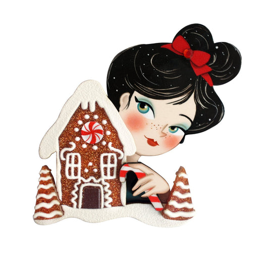 Cartoon girl brooch holding a gingerbread house, black hair with red bow