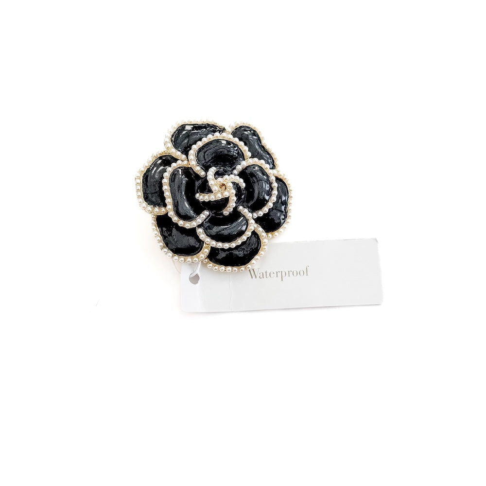 Black flower brooch with pearl trim, close-up with waterproof tag