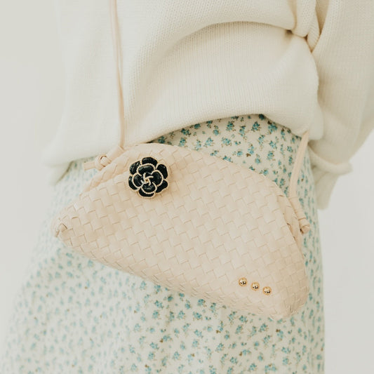 Black flower brooch with pearl trim, on a white braided strap bag