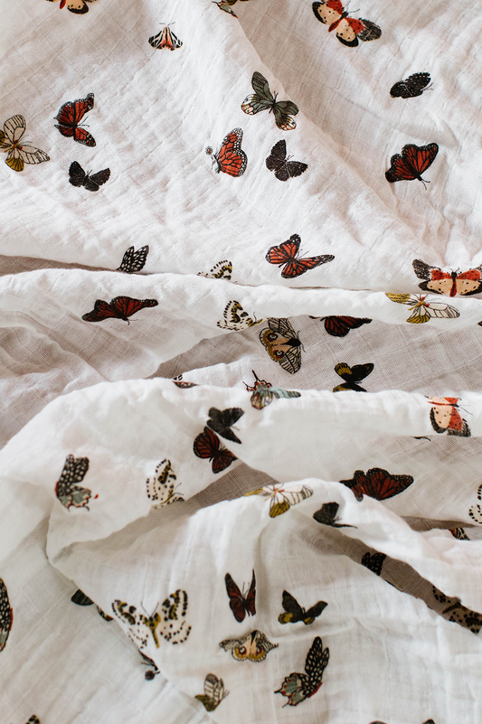 White butterfly printed muslin baby swaddle blanket, folded with multicolor wings