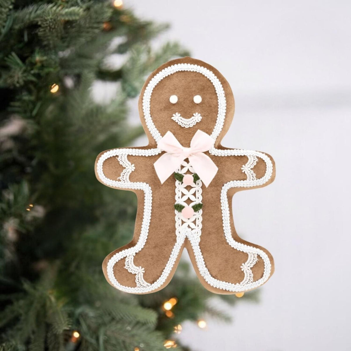 Gingerbread boy ornament with white icing border, pink ribbon bow, and lacy green panel