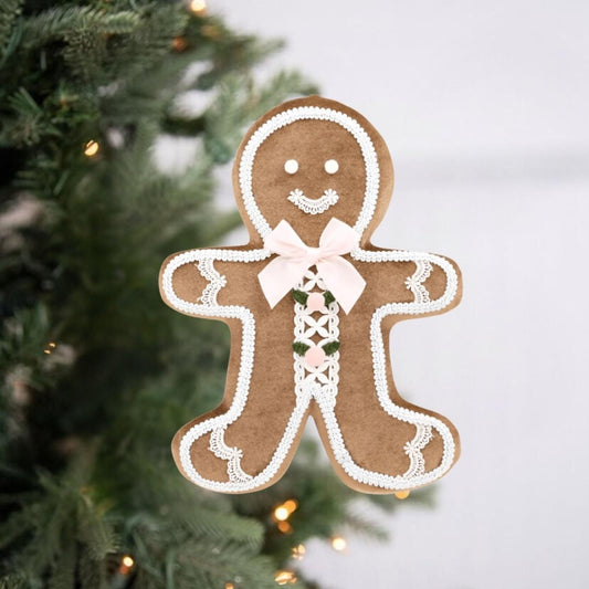 Gingerbread boy ornament with white icing border, pink ribbon bow, and lacy green panel