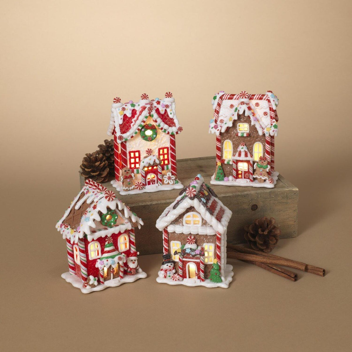 Four miniature gingerbread-style house ornaments with candy trim and glowing interiors