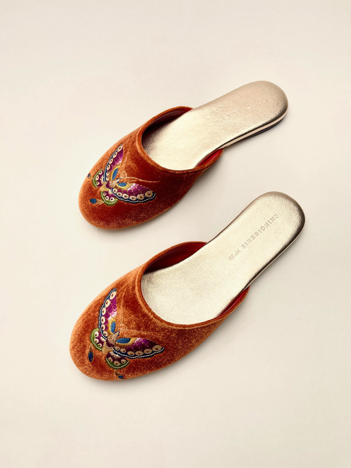 Burnt orange velvet mules with butterfly embroidery, open-back mule shape
