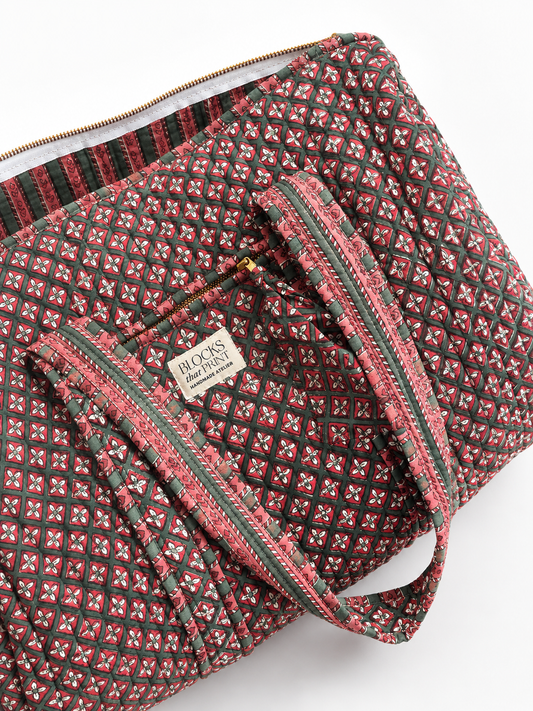 Quilted duffle bag close view, red-and-green geometric print, zip pocket, patterned trim