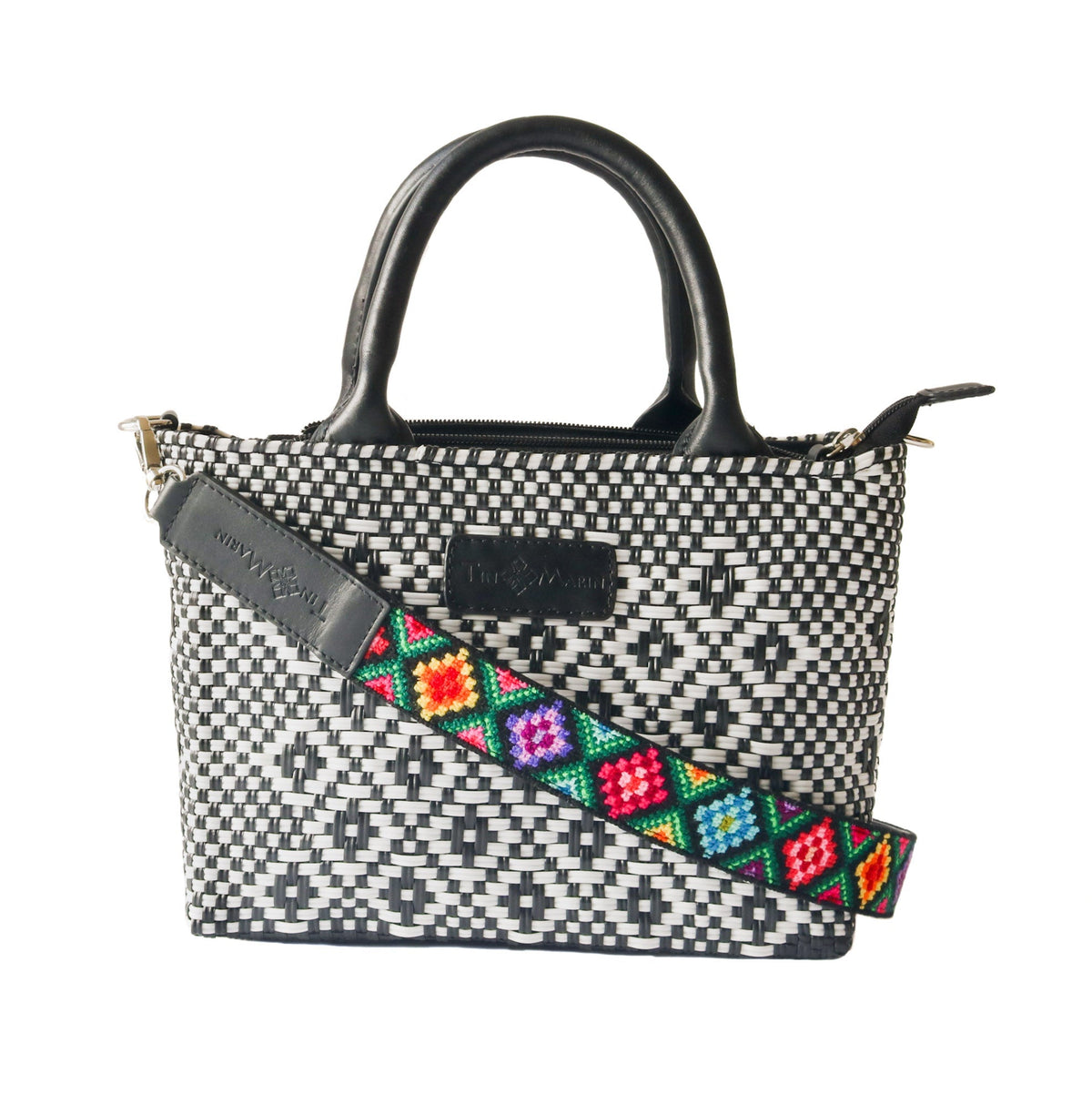 Small woven crossbody bag, black-and-white weave with black strap and multicolor patch detail.