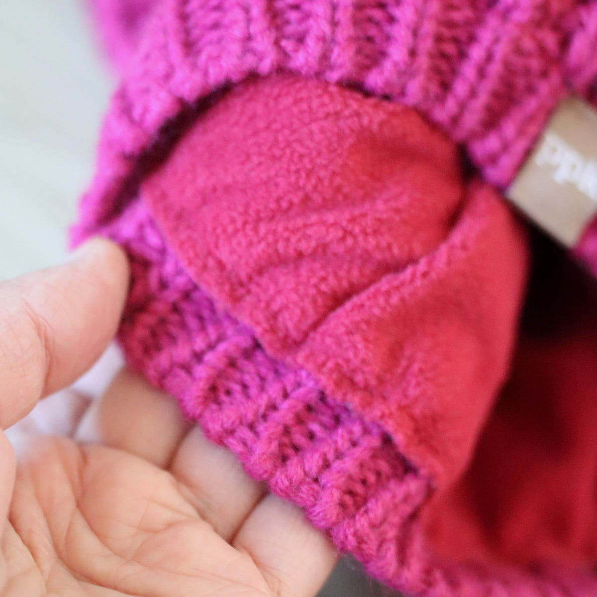 Plum knit beanie opened to show its soft fleece lining