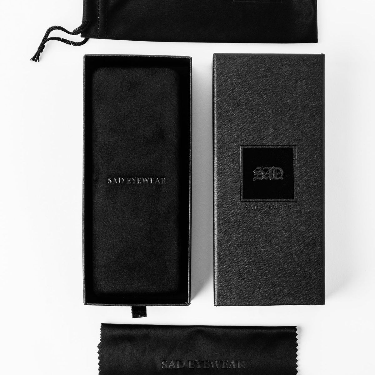 Sunglasses accessory set with black cloth pouch and two branded storage boxes.