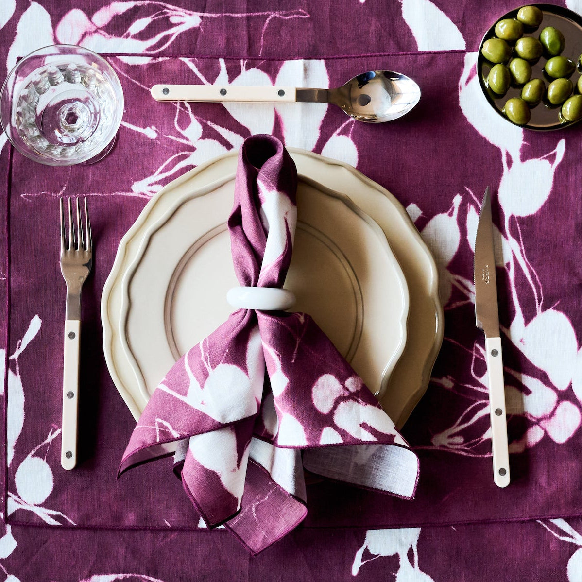 Aubergine placemat with light blue leaf floral pattern, styled on a table.