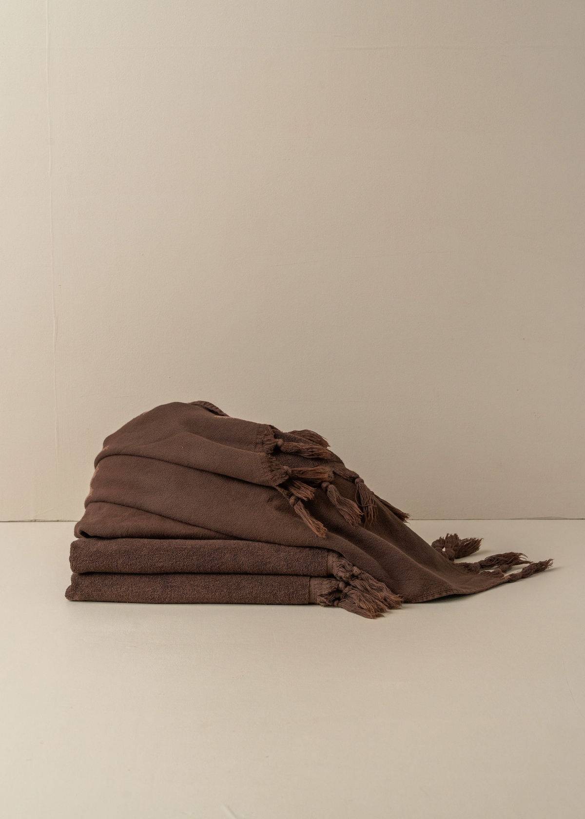 Folded dark brown Turkish hand towel with fringed edge