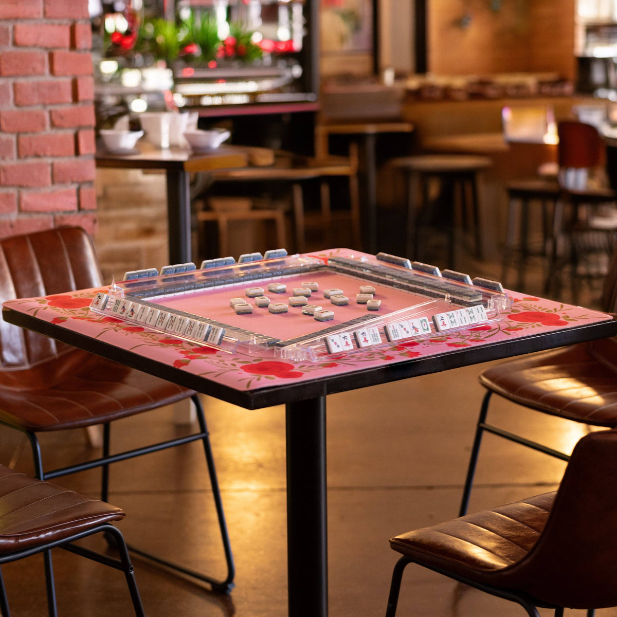 Pink floral mahjong mat spread on table with stacked tiles for gameplay