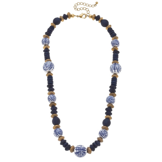 Navy painted wood bead necklace with blue-and-white swirl accents and gold clasp