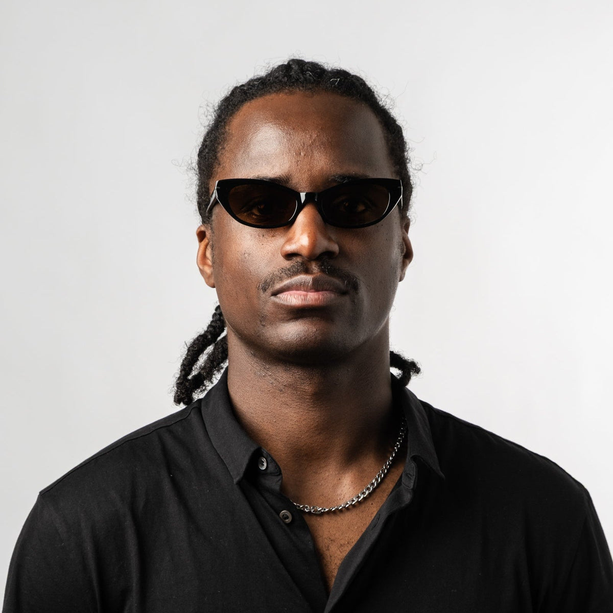 Person wearing black polarized sunglasses with bronze lenses, front portrait and necklace.
