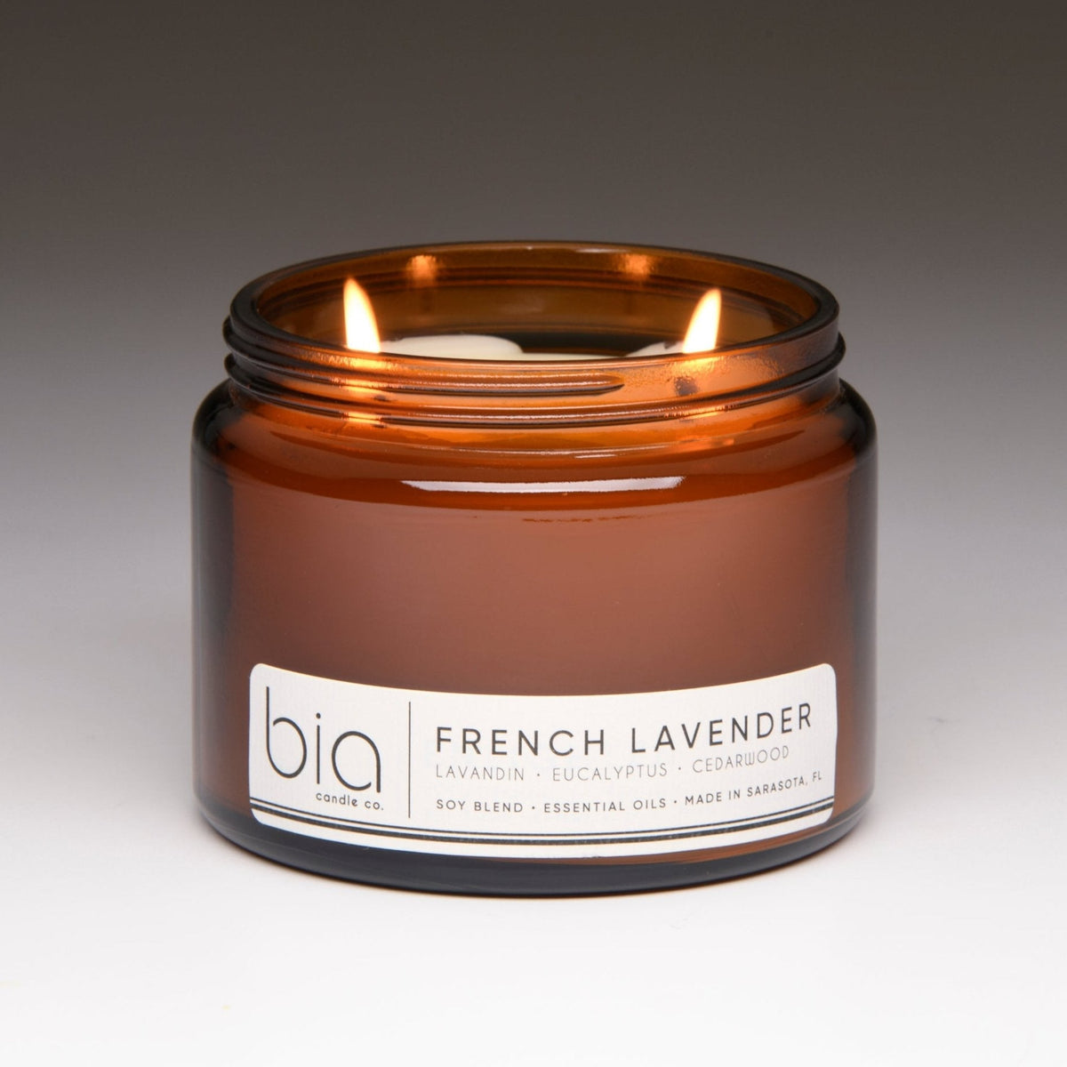 Amber soy candle jar with lit wick, front label and branding clearly visible