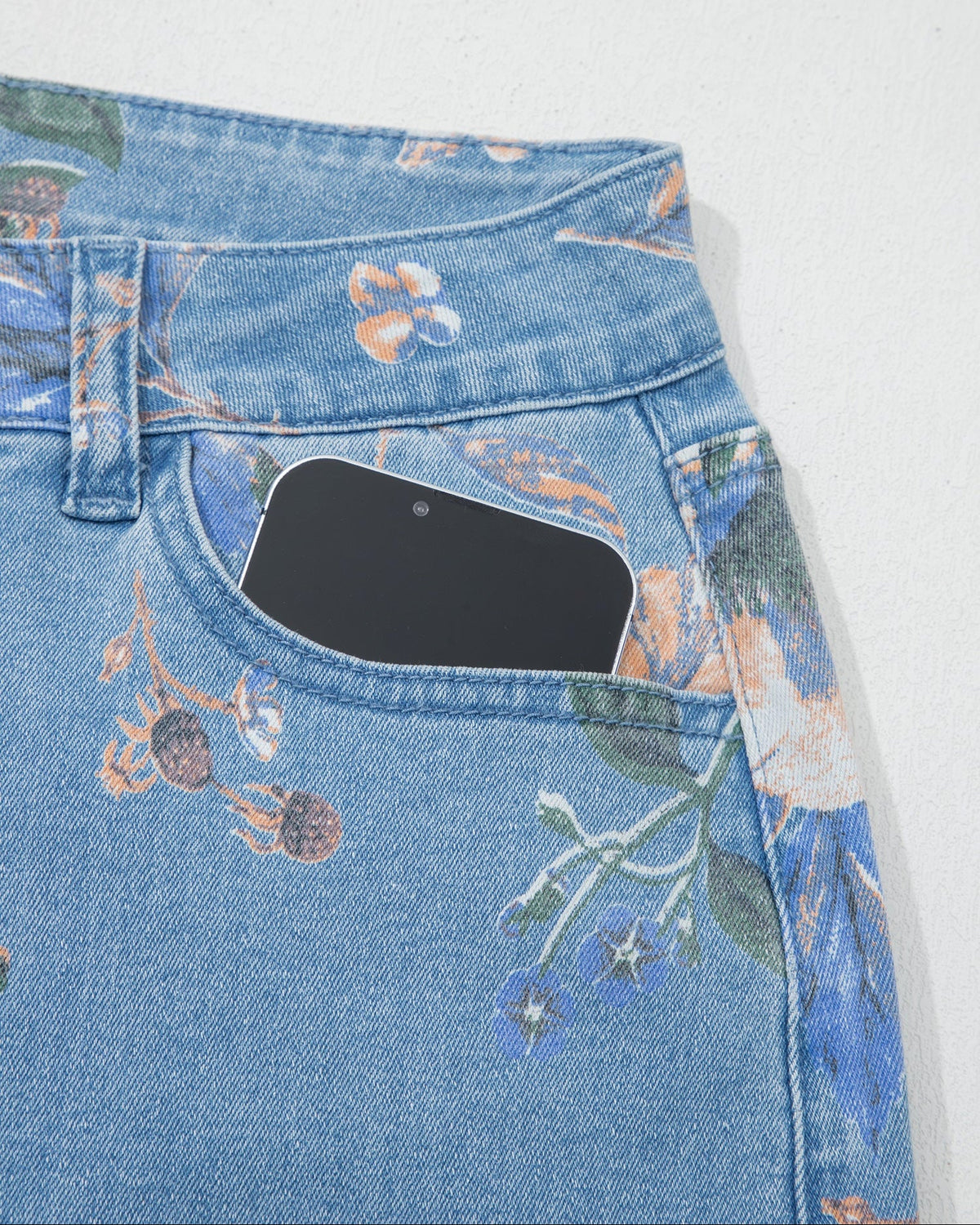 Light blue denim jeans detail with floral print, belt loops, and stitched front pocket