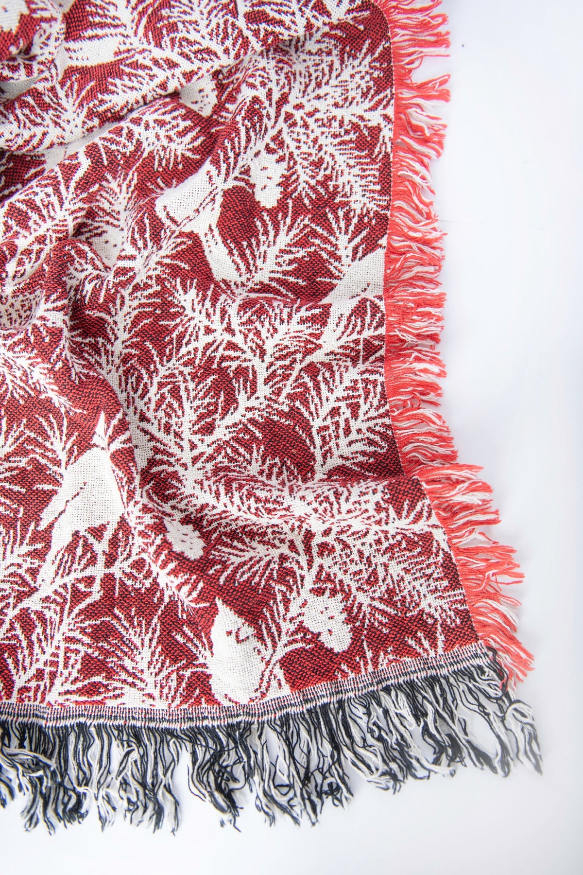 Close-up of cranberry red and cream jacquard throw with cardinal pattern and fringe
