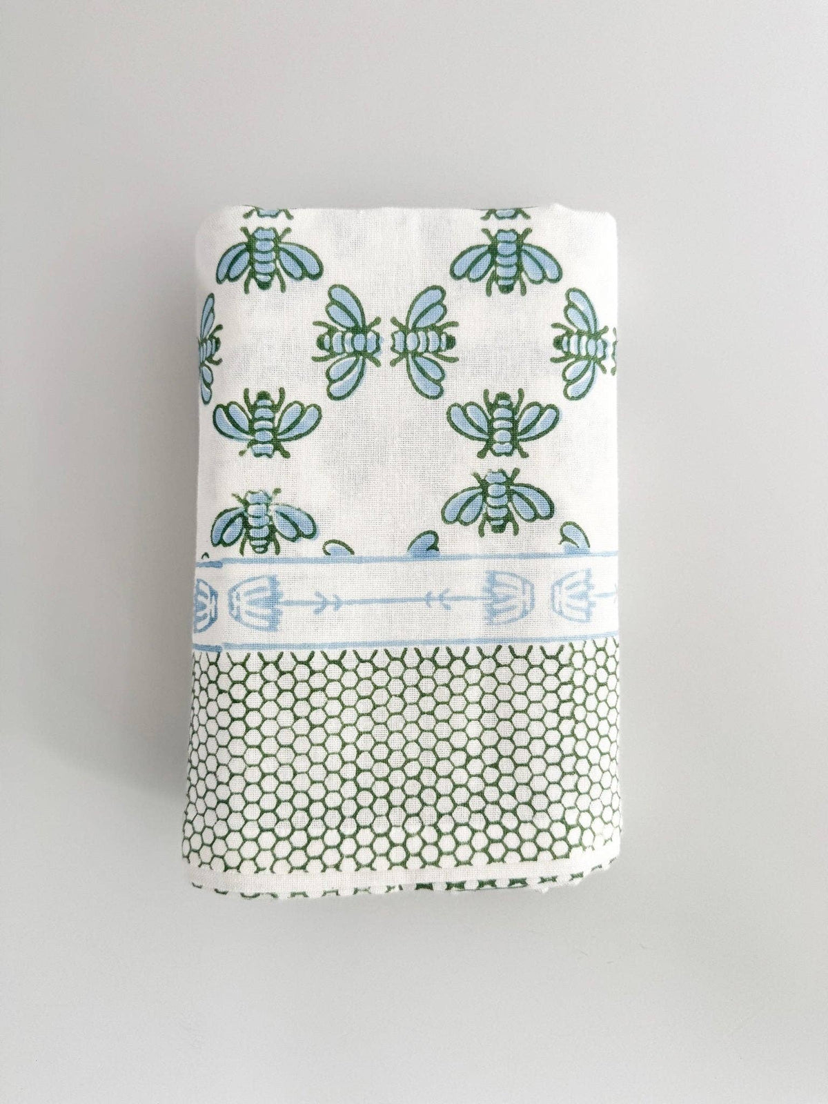 Table throw folded with blue-and-sage floral print and honeycomb-texture backing.
