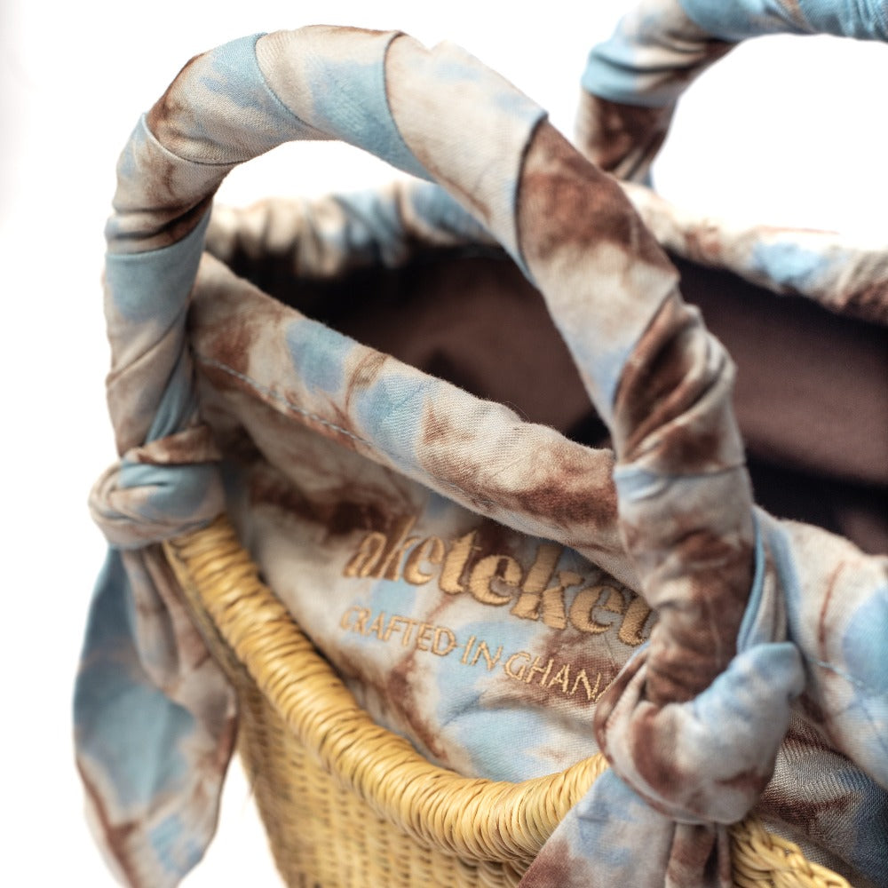 Small straw butterfly bag with braided handles and light blue patterned interior lining