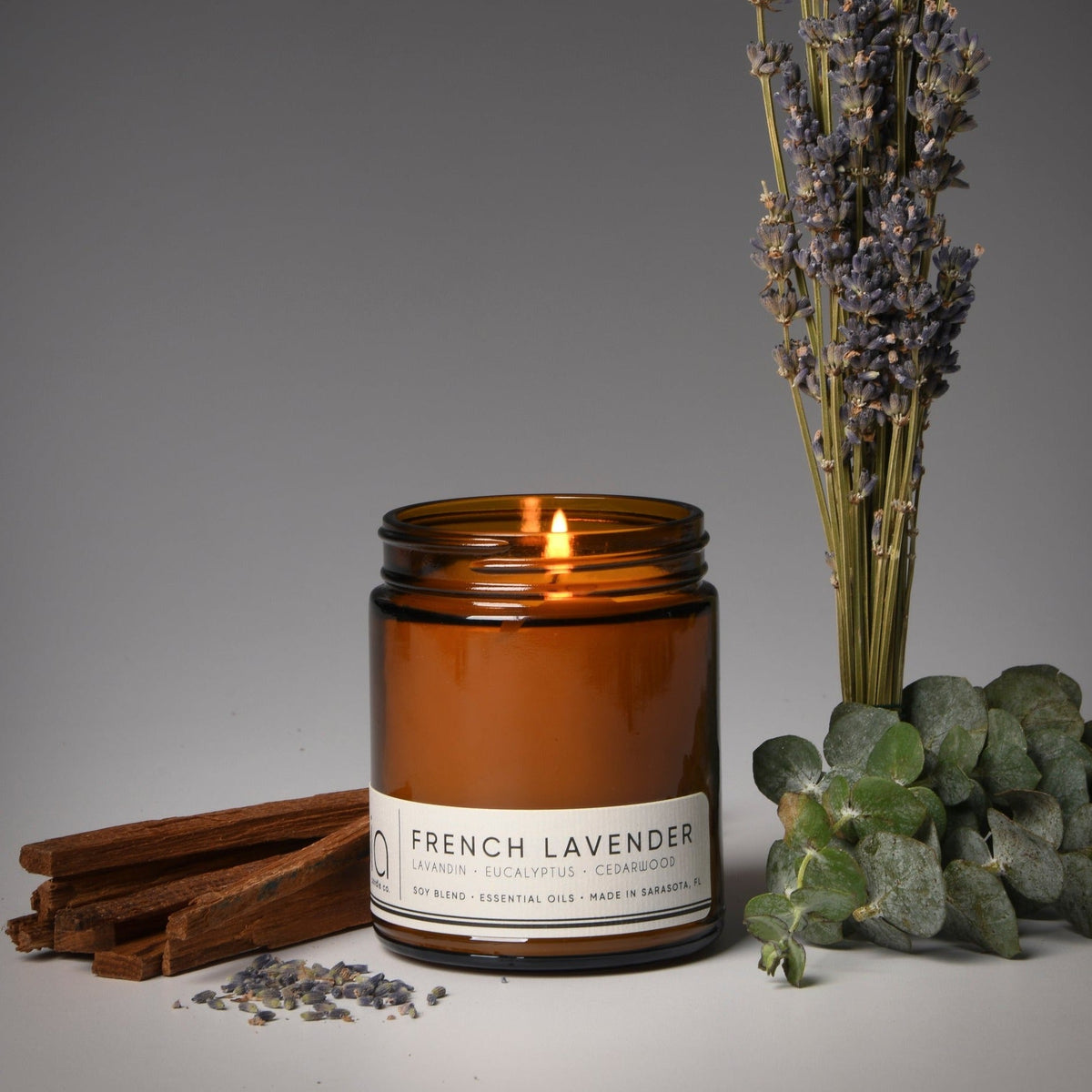 Amber soy candle in glass jar with lit flame, French Lavender label and lid ring